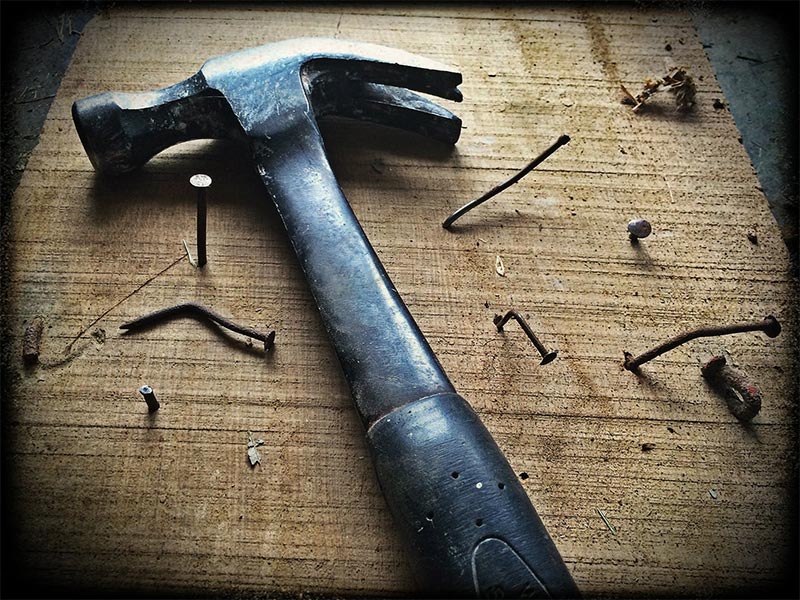 a hammer on a plank of wood with bent nails