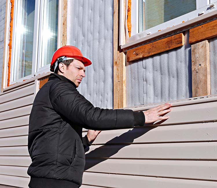 man in black vest replacing house siding